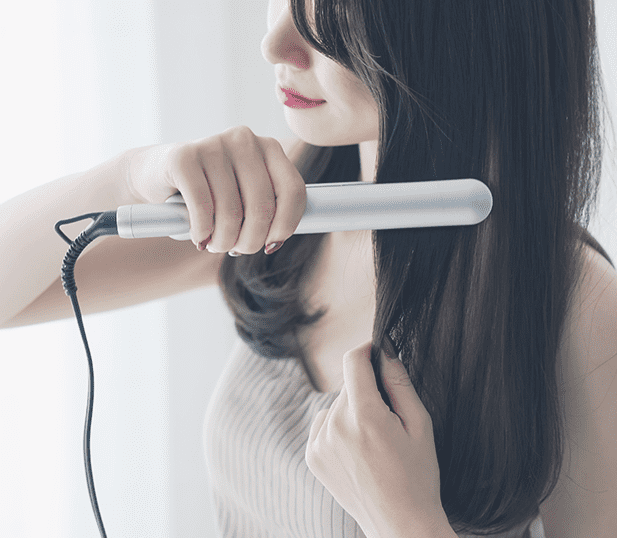 ストレートアイロンをあてる女性の画像
